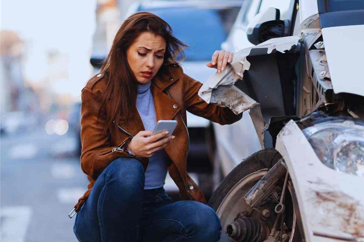 ragazza accanto ad auto incidentata